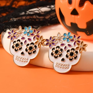 Halloween skull earrings with colorful flowers and gold trim on festive orange background