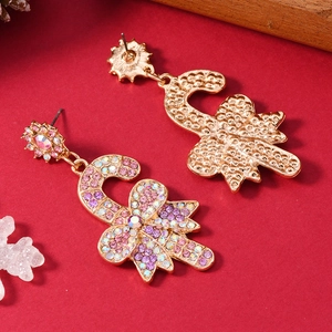 Dettaglio degli orecchini a bastoncino di zucchero con strass rosa e fiocco dorato