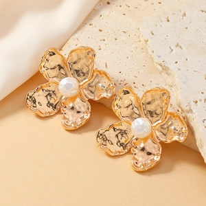 Boucles d'oreilles fleur dorée avec texture martelée et perle sur tissu de soie beige