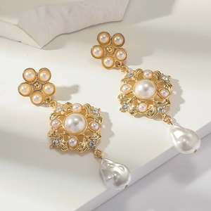 Détails de boucles d'oreilles baroques avec perles et monture dorée gravée de fleurs