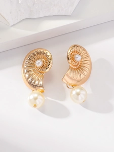 Vue macro de boucles d'oreilles conque dorées avec perles blanches et texture métal