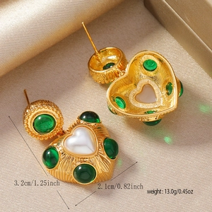 Détail des boucles d'oreilles en cœur avec pierres d'émeraude et incrustation de perles