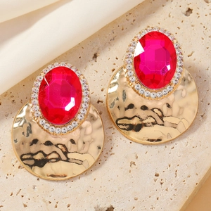 Detail of baroque style earrings with rose red gemstone and hammered gold metal finish