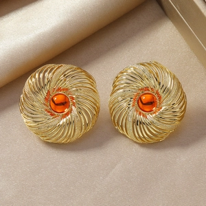 Detail of vintage gold spiral earrings with amber resin stones on silk background