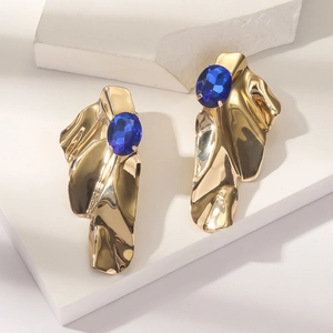 Detail of gold alloy heart earrings with lava texture and deep blue zircon stones