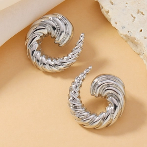Macro detail of silver twisted horn earrings with spiral texture on warm background