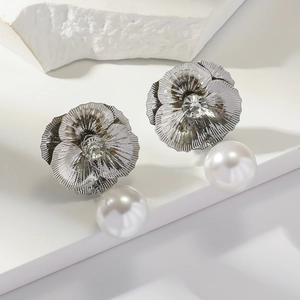 Macro detail of silver flower earrings with radiant petal texture and pearl drop
