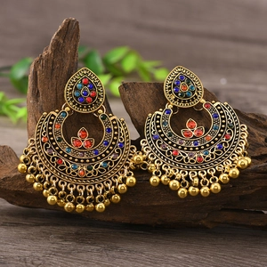 Vintage bohemian drop earrings with colorful beads and metal tassels on wood background