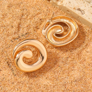 Macro detail of golden spiral earrings with size dimensions 2.5cm by 2.4cm on a stone surface