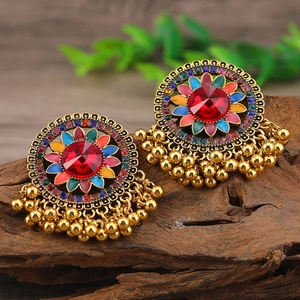 Macro di orecchini etnici boho con pietre rosse e nappe multicolore su legno scuro