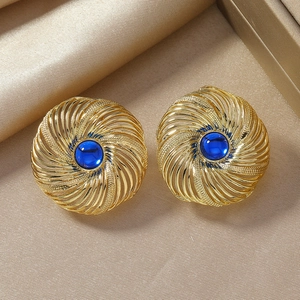 Retro golden twist earrings featuring deep blue center gemstone on champagne silk