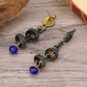 Dettaglio di orecchini bohémien con perline di cristallo blu e campanelli di bronzo