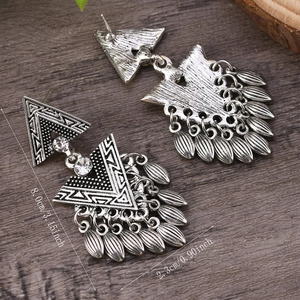 Dettaglio orecchini stile boho con pendenti e misura di 8,0 cm su legno scuro