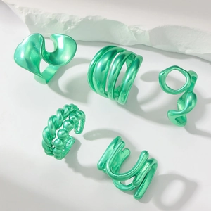 Macro shot of 5-piece set of vibrant metallic green rings with fluid geometric shapes
