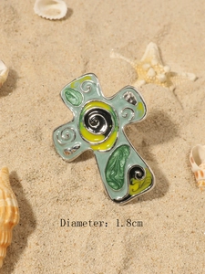 Dettaglio macro di gioielli a croce in smalto con motivo a spirale e misura diametro 1,8cm