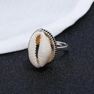 Vue macro de la bague argentée avec coquillage cauri naturel et détails de perles rétro