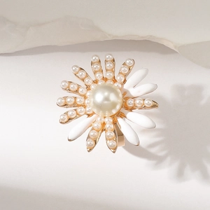 Gros plan sur une bague fleur dorée avec pétales superposés et une perle centrale