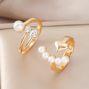 Details von eleganten vergoldeten Ringen mit weißen Perlen und Zirkonia auf Seidenhintergrund