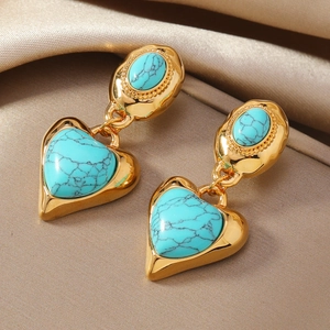 Orecchini vintage a cuore in oro con pietre turchesi su sfondo di raso color champagne