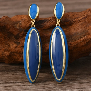 Vintage style gold and blue enamel drop earrings displayed on a rustic wood block