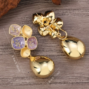 Detail view of vintage enamel floral earrings with polished gold teardrop pendants