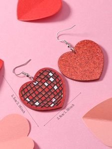 Detail view of heart-shaped acrylic earrings with red glitter and retro checkered patterns