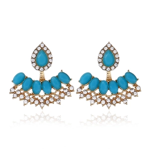 Detail of vintage gold earrings with turquoise stones and shimmering crystal accents