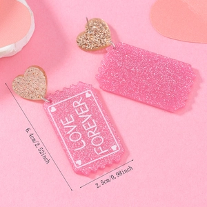 Detail shot of pink glitter acrylic heart earrings with Love Forever text print