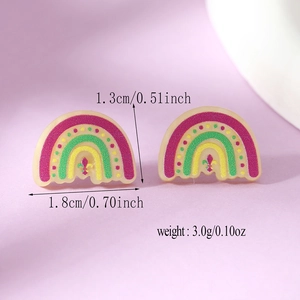 Detail of semi-circular rainbow acrylic stud earrings with golden fleur-de-lis emblem