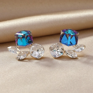 Exaggerated geometric earrings with blue crystal cubes and tassels on silk background
