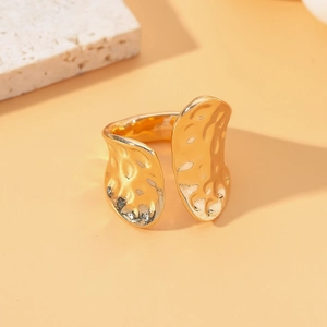 Golden open ring with irregular hammered lava texture on a minimalist stone display