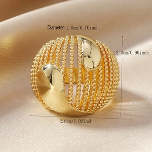 Macro view of a large golden hollow cage ring with teardrop metallic details on satin