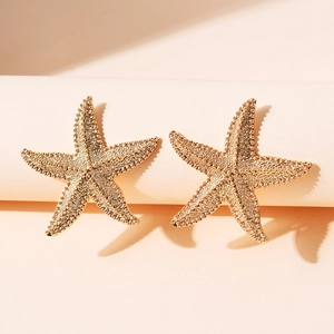 Boucles d'oreilles étoiles de mer dorées avec finition perlée sur un socle blanc