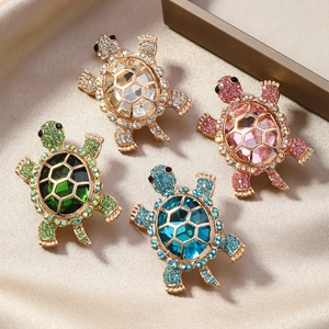 Vue détaillée de broches tortue colorées avec cristaux sur fond de soie élégant
