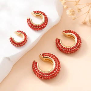 Détails de quatre boucles d'oreilles C en strass rouges sur base dorée