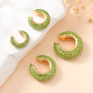 Détail de quatre bagues d'oreilles dorées en C serties de cristaux de zircon vert