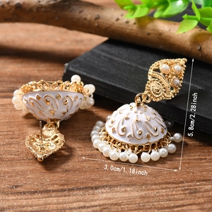 Detail view of ethnic Jhumka earrings with white enamel patterns and pearl accents