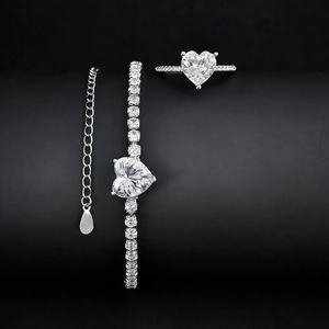 Detail view of heart-shaped zircon jewelry set with tennis bracelet and ring on black background