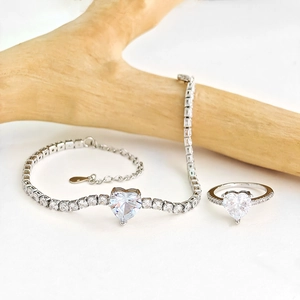 Close-up of heart-shaped zircon jewelry set with tennis bracelet and ring on wood branch