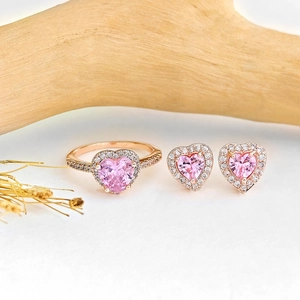 Schmuckset mit rosa Herzzirkon, Ring und Ohrringen aus Roségold auf Holzuntergrund