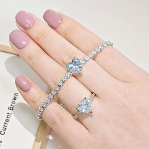 Macro detail of heart-shaped blue stone bracelet and clear zircon ring set in silver
