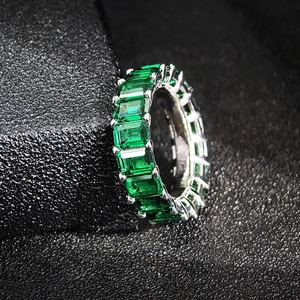 Vue latérale macro de la bague d'éternité argentée avec zircons verts taille émeraude