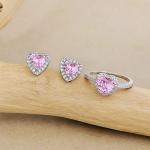 Nahaufnahme eines Schmucksets mit rosa Herz-Zirkonia, Ring und Ohrringen auf Holz