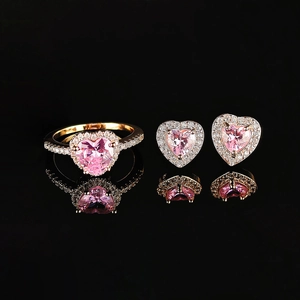 Nahaufnahme von rosa Herz-Zirkonia-Schmuckset mit Kristallen auf schwarzem Reflexionsgrund