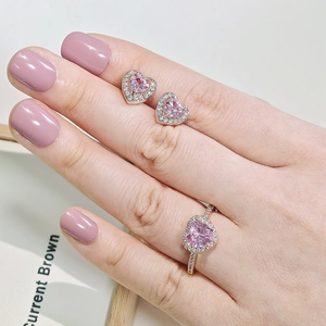 Nahaufnahme von rosa Herz-Zirkon-Schmuckset mit Roségold-Ring und Ohrringen am Modell
