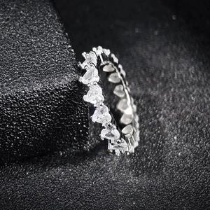 Close-up of eternity ring with heart-cut clear zircons on black textured background