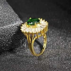 Macro detail of emerald synthetic zircon ring with gold band and baguette crystals