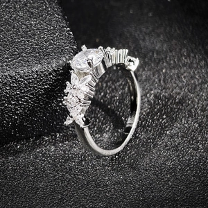 Silver marquise ring with round cut zircon and floral accent on textured black background