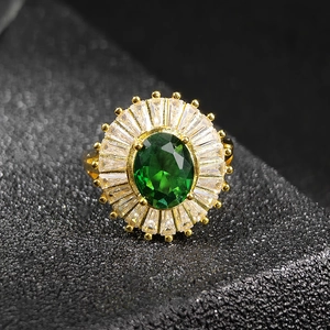 Macro shot of oval emerald green zircon ring with sunburst halo and gold band