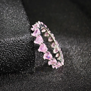 Close-up of pink heart-cut gemstones set in a silver eternity ring band for women